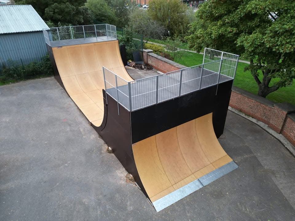 Kleine Halfpipe aus Holz mit Metallgeländern auf den Plattformen