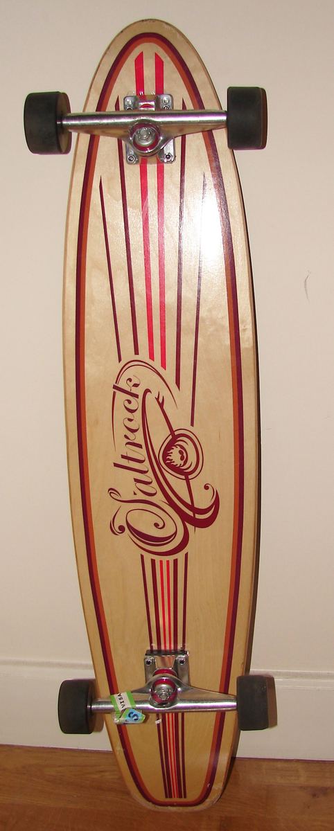 Longboard aus Holz mit roter und weißer Grafik, senkrecht an eine Wand gelehnt